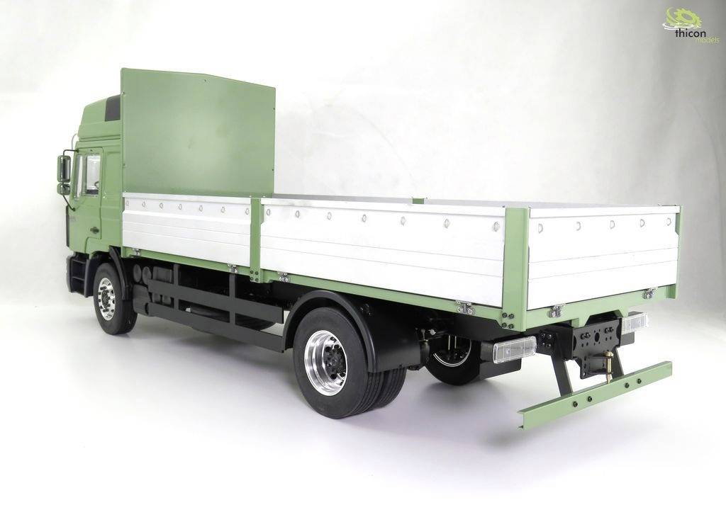 A green lorry with an open flatbed is positioned sideways on a white background. There is no visible cargo.
