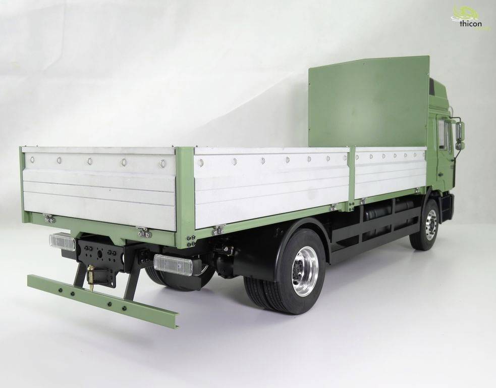 A green lorry with an open flatbed, photographed from the rear in a studio.