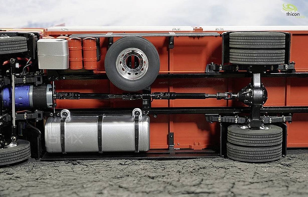 Stationary lorry trailer lying on a concrete surface, with axle and tyres visible. Displays underside details including axles and fuel tank.