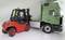 A red forklift is loading wooden pallets onto the loading bay of a green lorry. One person is operating the forklift.