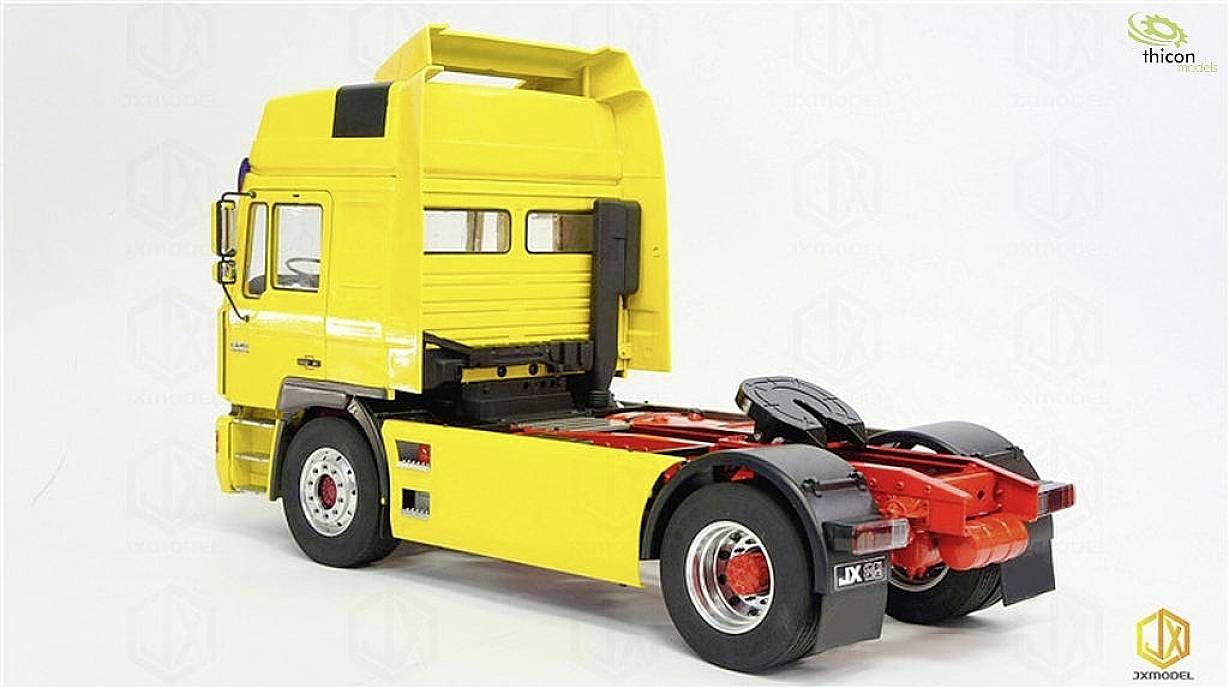 Yellow model of a lorry without a trailer, positioned on a white surface, shows details of the driver's cab and chassis.