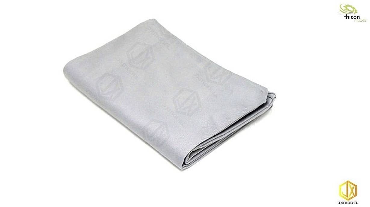 Folded, light grey cloth with a subtle pattern, resting on a white background. Small logos visible in the top right and bottom right corners.