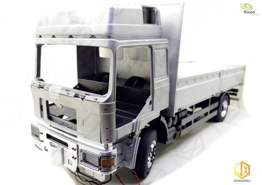 Silver-coloured model lorry with missing cab and load area. No driver's cab roof, revealing internal structure and side details.