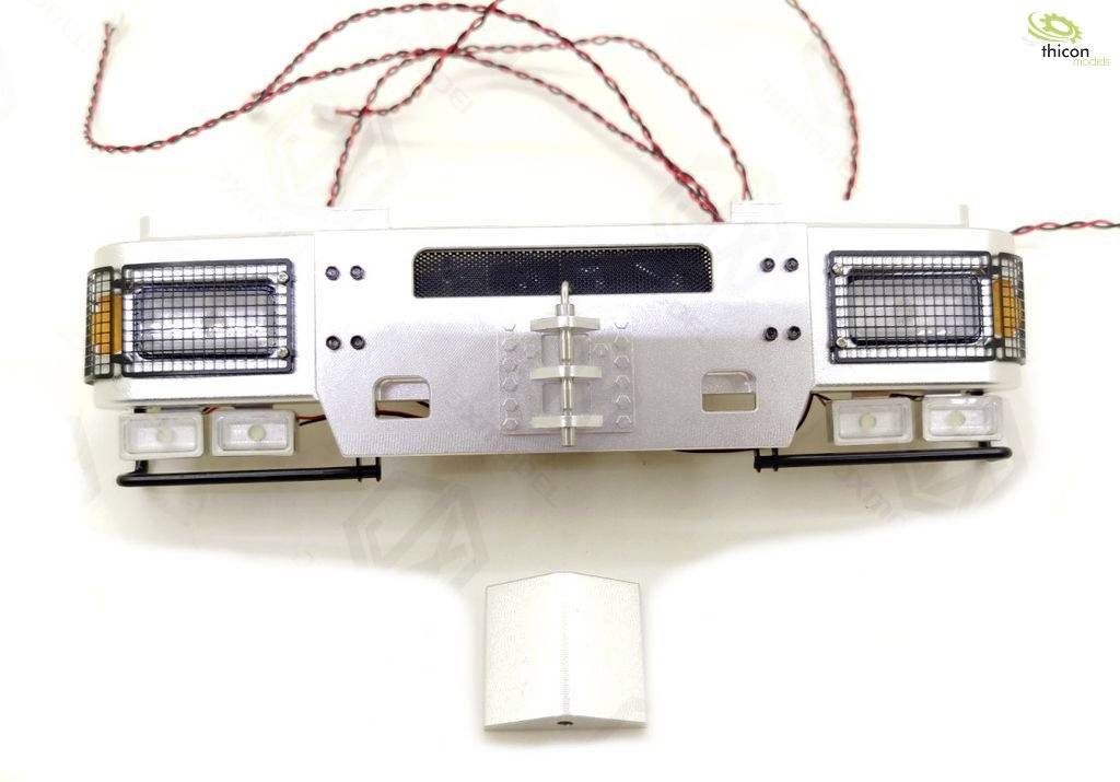 Lorry model front with headlights, indicators and bumper, cables in the background. Part of a Thicon model.