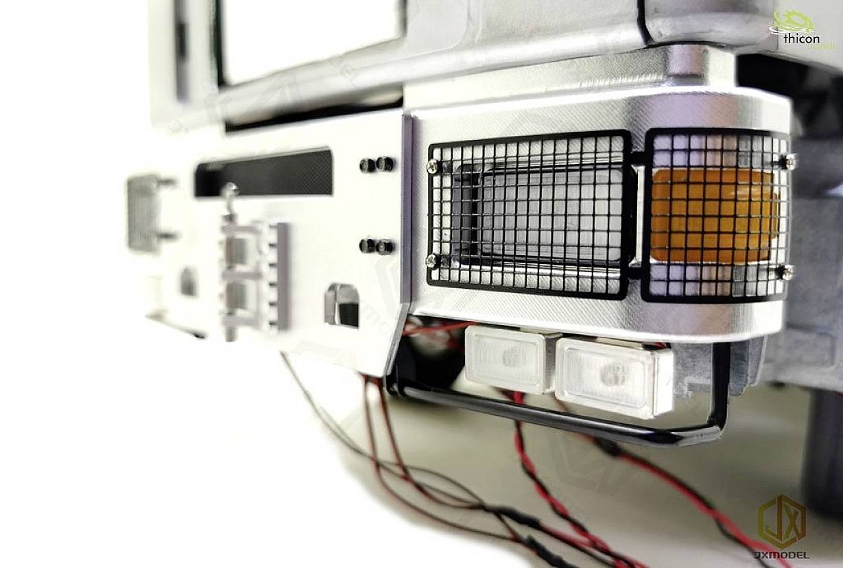 Close-up of a silver engineering component with fine grids, multiple rectangular lights, and exposed cables in the foreground.