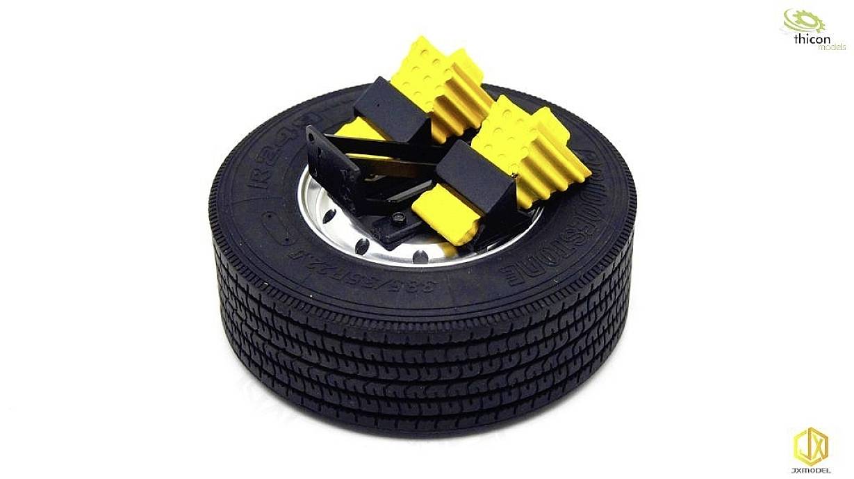 Black tyre with yellow wheel chocks on top. These are used to secure the tyre to prevent it from rolling.