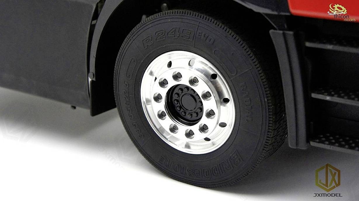 Close-up of a lorry tyre with a silver wheel rim. The tyre is attached to a black lorry. A logo is positioned in the top right corner.