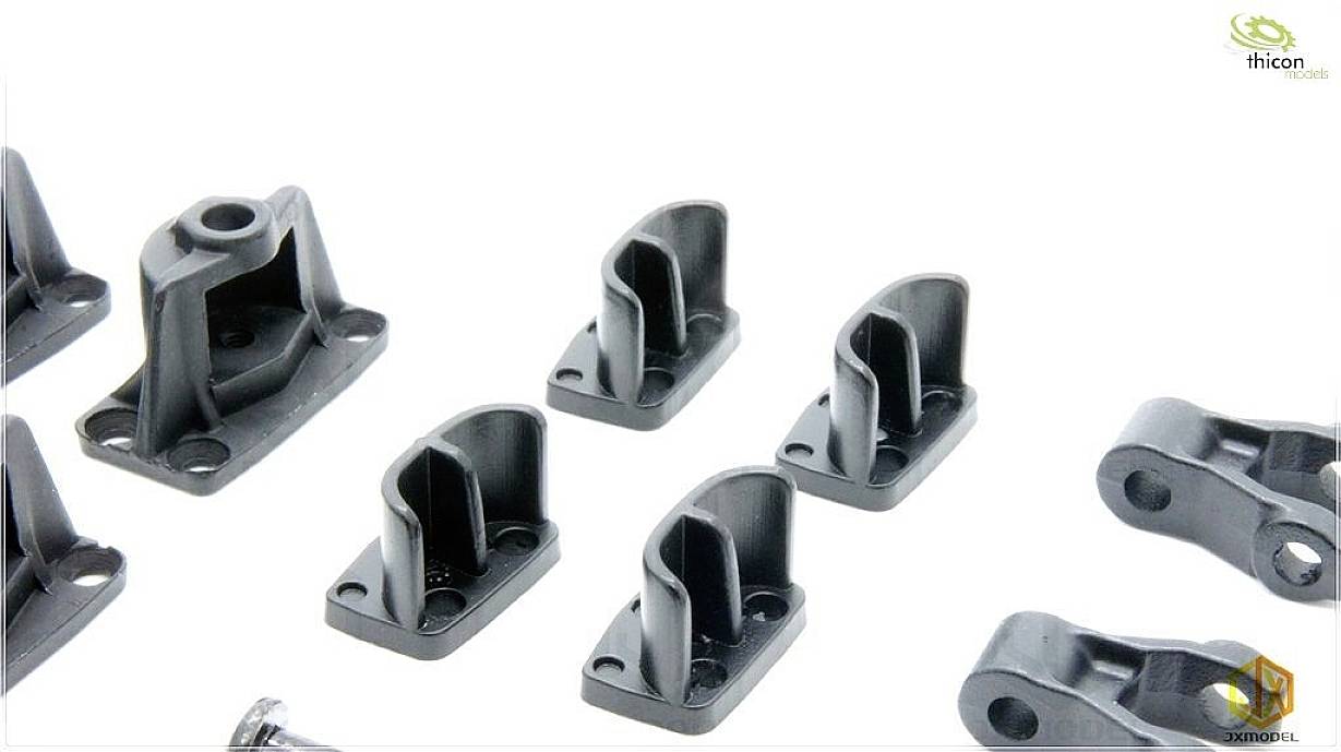 Black plastic holders of various shapes and sizes are lying on a white surface.
