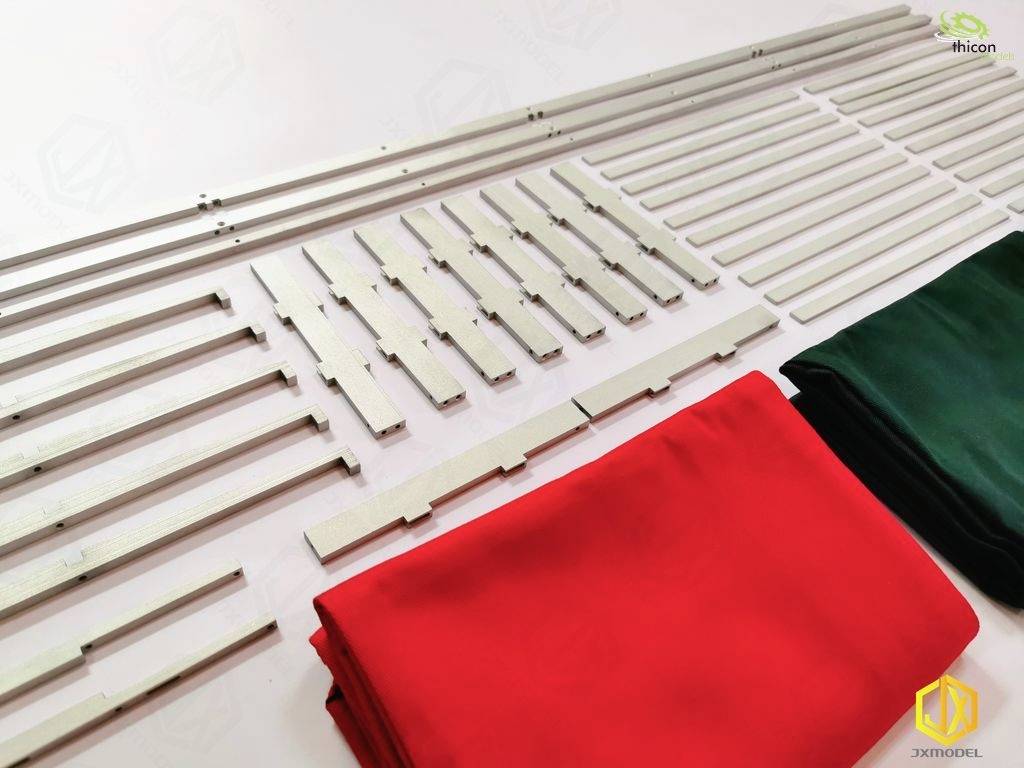 A table mat with metal rods and red and green fabrics. Accessory parts are laid out flat on a white surface.