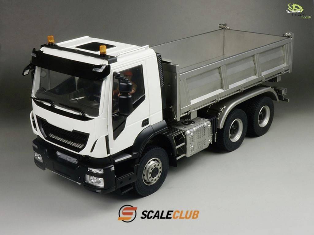A model lorry with a tiltable loading bed in a studio shot. The lorry is white with black details and has six wheels.