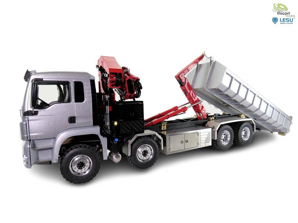 Silver lorry with raised tipper body, four axles and red loading crane, side view.