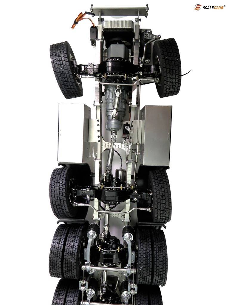Chassis view of a model lorry from underneath, showing multiple axles and details of wheel suspensions and drive components.