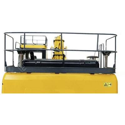 A yellow industrial machine with a metal platform and railings on top. A safety warning symbol is attached to the side.
