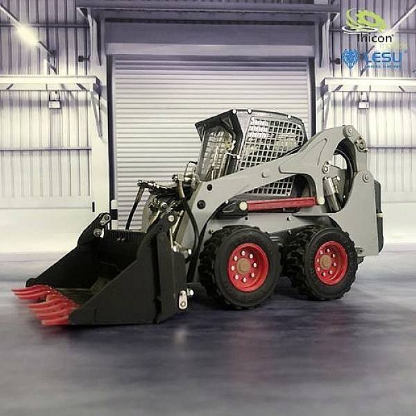 A grey mini loader with a red bucket attachment stands in an industrial hall. A large roller shutter door is visible in the background.