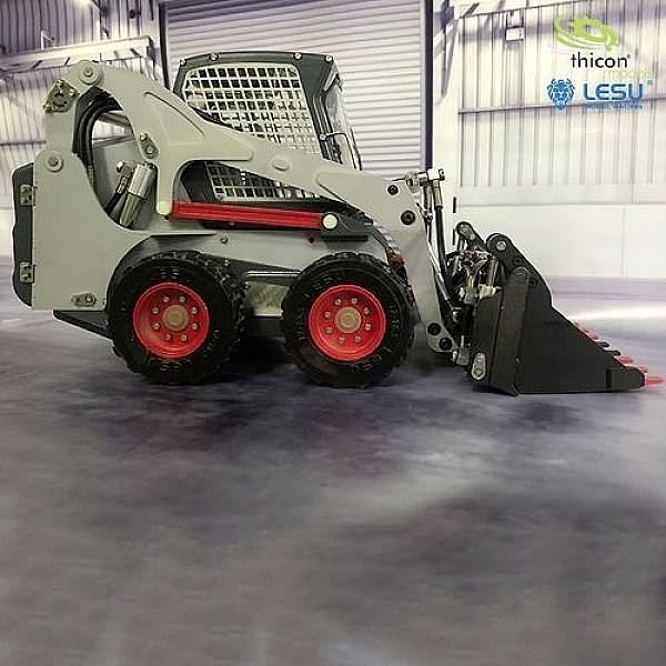 A compact wheeled loader with a bucket in a hall, aligned to the right. 'Thicon' and 'LESU' markings are visible in the upper area of the image.