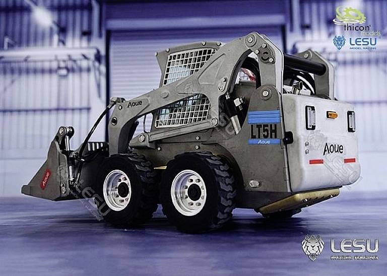 A silver model loader with the inscription 'LT5H' stands in a large hall. The loader displays movable parts and robust wheels.