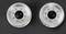 Two silver aluminium wheel nut covers on a black background, each with six holes around a central black hub.