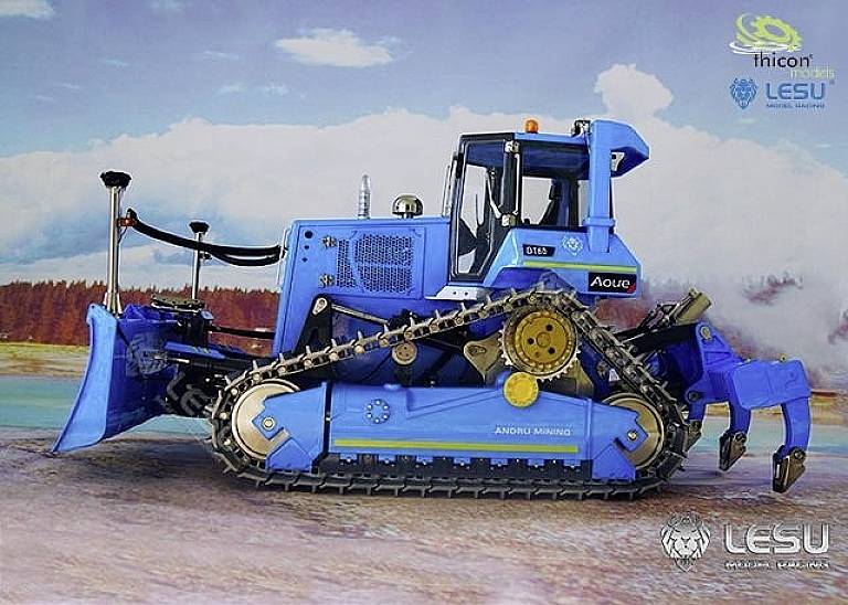 Blue toy bulldozer on a coloured surface outdoors, with brand logos and a clear sky in the background.