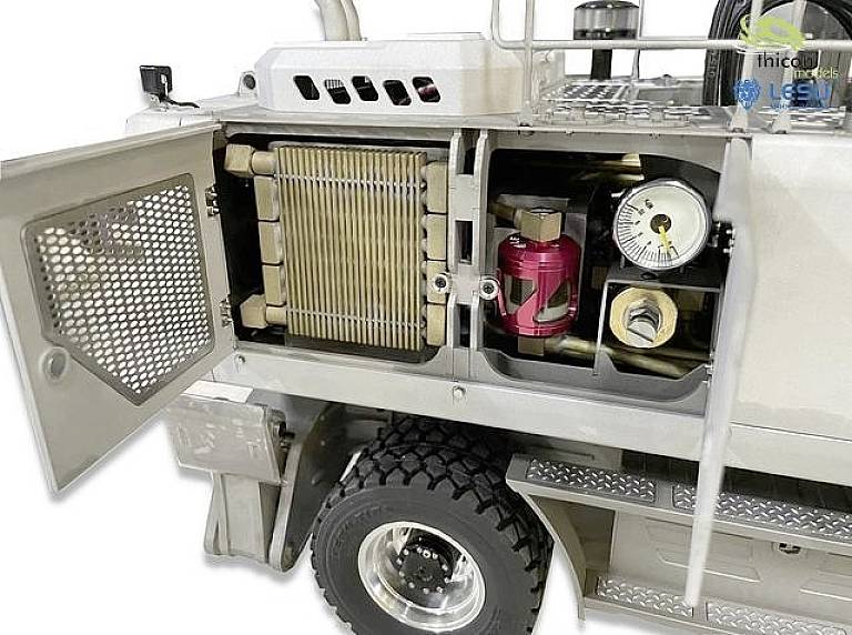 An opened engine compartment of a commercial vehicle shows a radiator, a pressure gauge and other technical components.