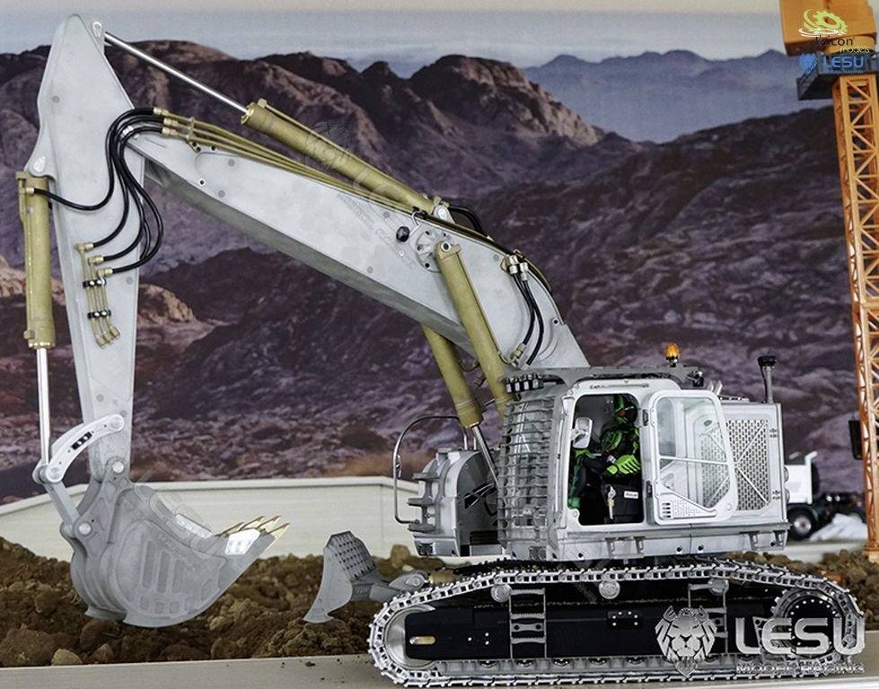 A model of a silver excavator on a diorama with a rocky background. The excavator has a movable bucket and tracked wheels.