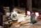 A person is sawing wood with a circular saw in daylight, while a work lamp with two illuminated lights is lighting the scene.