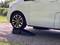A white car is partially positioned on a ramp. The front axle is raised, while the rear axle remains on the ground.