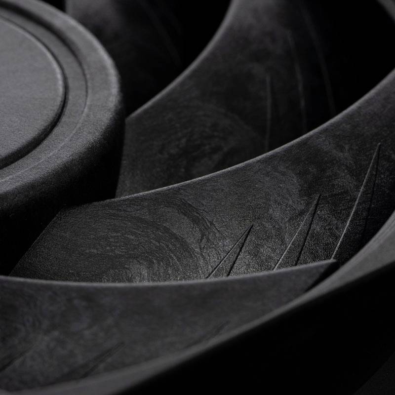 A close-up of a black speaker reveals the texture and details of the membrane and grooves on a dark surface.