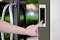 A hand is tapping on a digital door unlocking screen with a number pad next to a glass door.