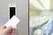 A hand holds a key card in front of an electronic door lock, beside a meeting room with a round table and white chairs.
