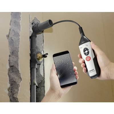 A hand is holding an endoscopic tool, which is inspecting a water pipe through a wall opening. The other hand is holding a smartphone displaying the endoscope image.