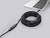 A black HDMI cable is connected to an open laptop. The cable is coiled and fitted with an amplifier in the middle.