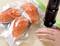 Three salmon fillets in a vacuum bag are sealed with a vacuum device. A hand holds the bag steady.