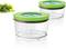 Two transparent, round food storage containers with green lids next to fresh spinach. Containers by Bosch, suitable for storage.