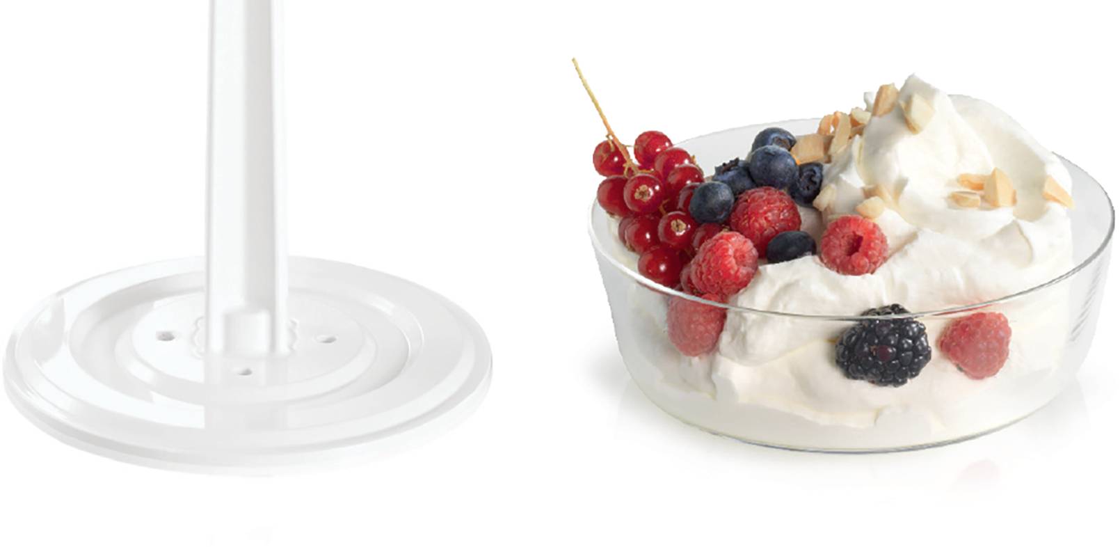 A glass container with cream, garnished with redcurrants, blueberries, raspberries, blackberries, and flaked almonds.
