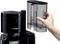 A black Bosch coffee machine with a removable, transparent water tank. A hand is holding the tank for easy refilling.