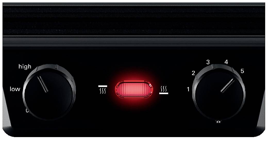 Close-up of a heating device control panel with two rotary knobs, with temperature regulation on the left (high/low) and on the right (1-5). A red indicator light is illuminated in the centre.
