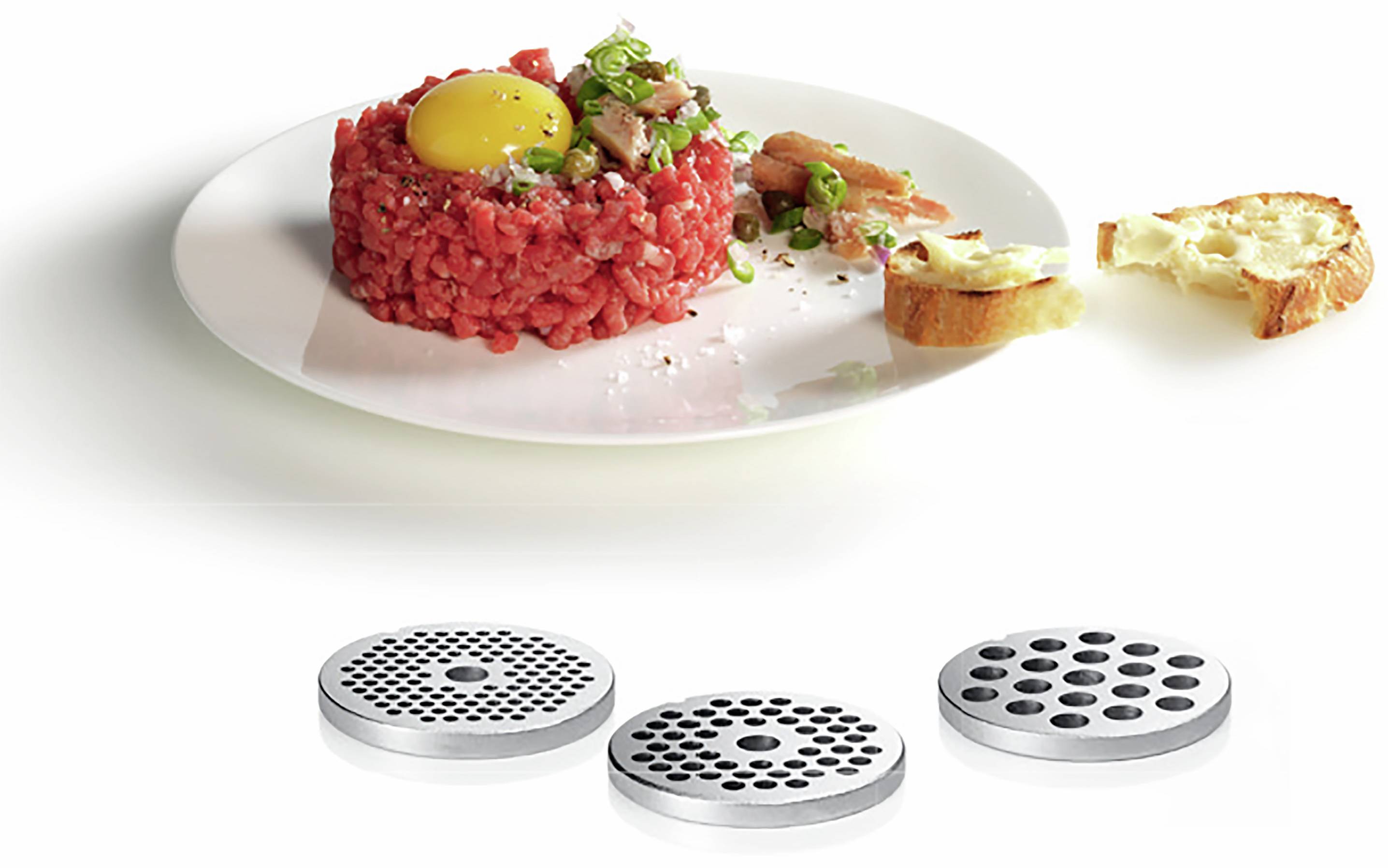A plate of beef tartare, raw egg yolk and garnish; served with bread. Underneath are three meat insert discs for a mincer.