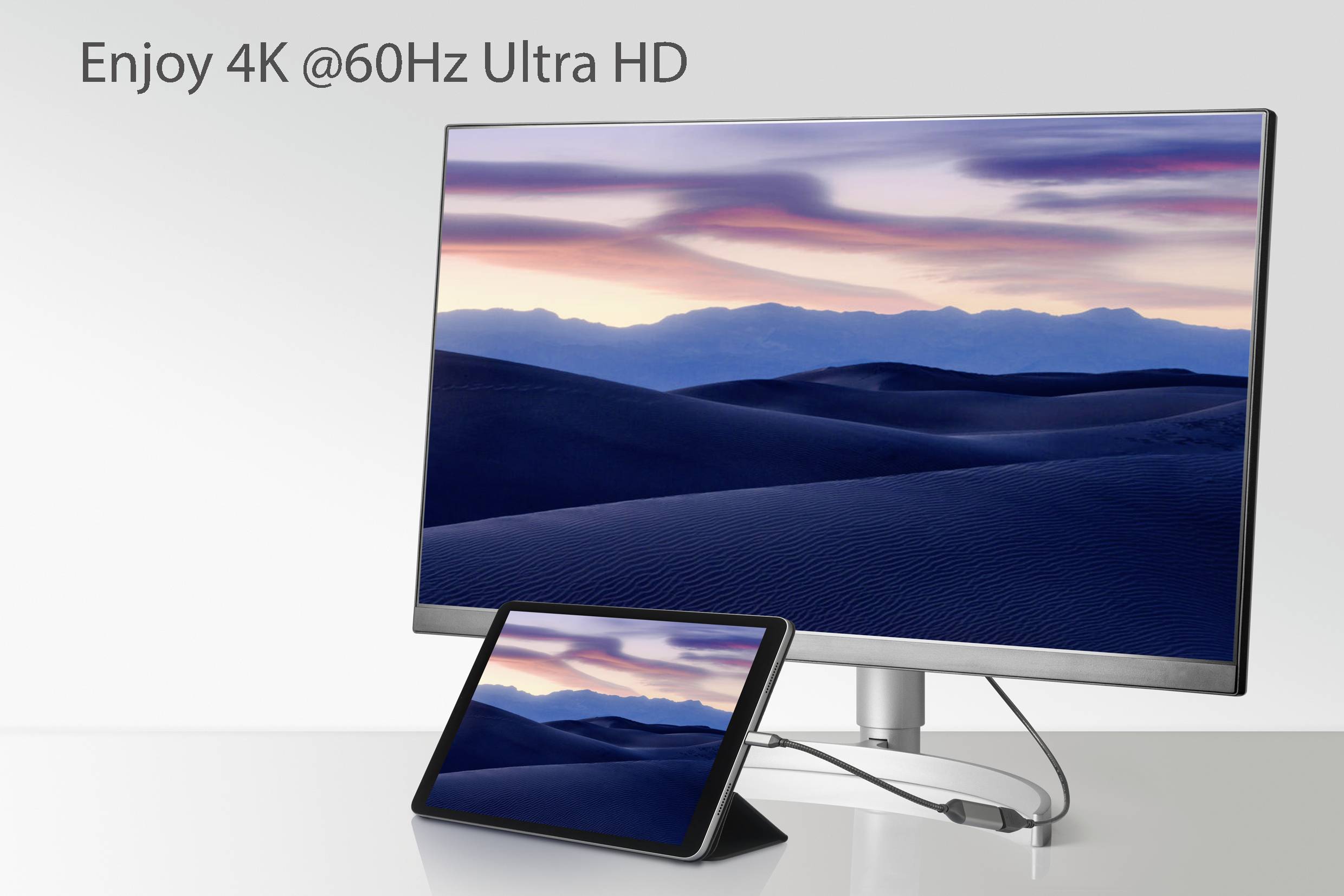 A monitor and a tablet are connected by a cable. The screen displays a desert landscape at sunset. Text: 'Enjoy 4K @60Hz Ultra HD'.<br><br>Note: This translation is already effectively in British English, as it uses standard English terminology and spelling.