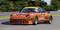 An orange racing car with the number 12 is driving on a racing circuit. The car is adorned with prominent brand logos.