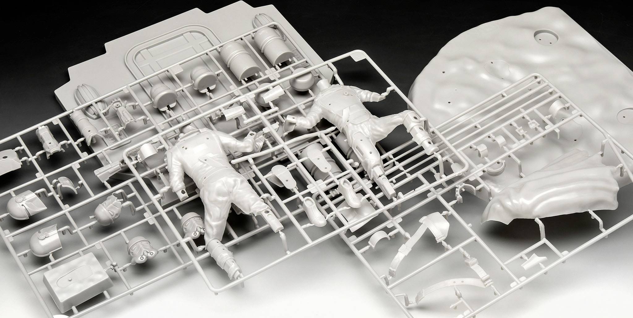 Several plastic model kits with parts for figures, helmets, and tools are spread out on a surface.