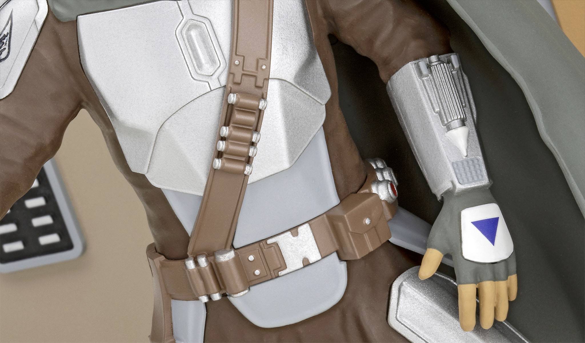 A toy figure in sci-fi armour with brown and silver elements and a blue triangular marking on the glove.