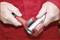 A person is using a red tool to adjust a metal pipe cutter on a silver pipe.
