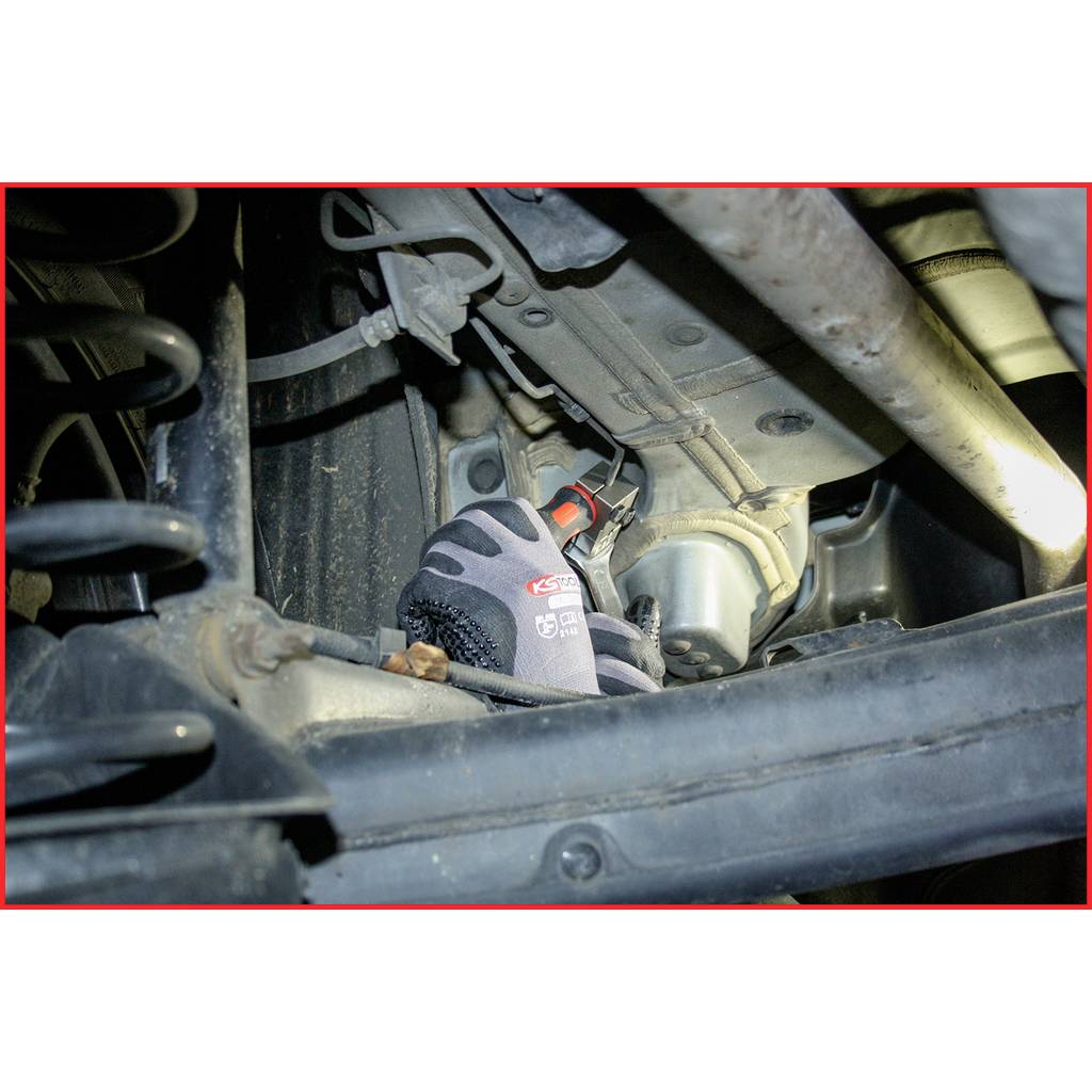 A close-up of a car part with a likely repairing glove. Metal structures and mechanics are visible.