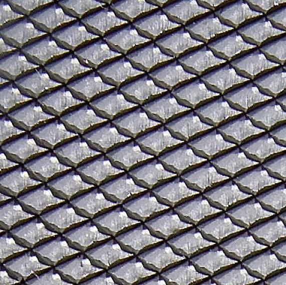 Close-up of a silver-coloured fish scale pattern, evenly and regularly distributed. Light reflections emphasise the structure.