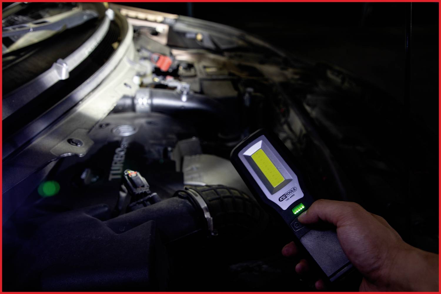 A person shines a handheld torch onto the engine bay of a vehicle. Various engine components are visible.
