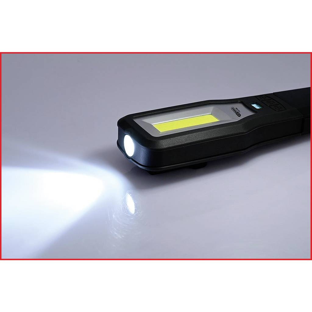 A black LED torch shines brightly on a glossy surface. The beam of light is directed to the left.
