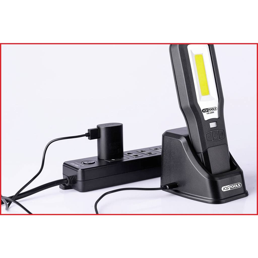 A portable LED lamp by KS Tools in a charging station, connected to a power strip, on a white background.