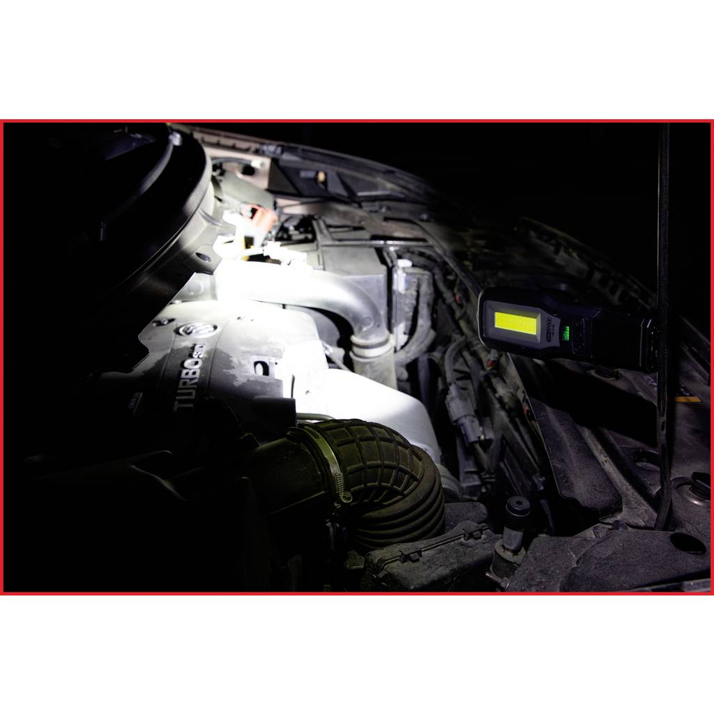 'Car engine compartment with a bright work light illuminating the engine block to make repair work visible.'