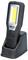 Portable LED work light in charging station. Black casing, yellow light panel at the front. Brand logo and buttons visible.