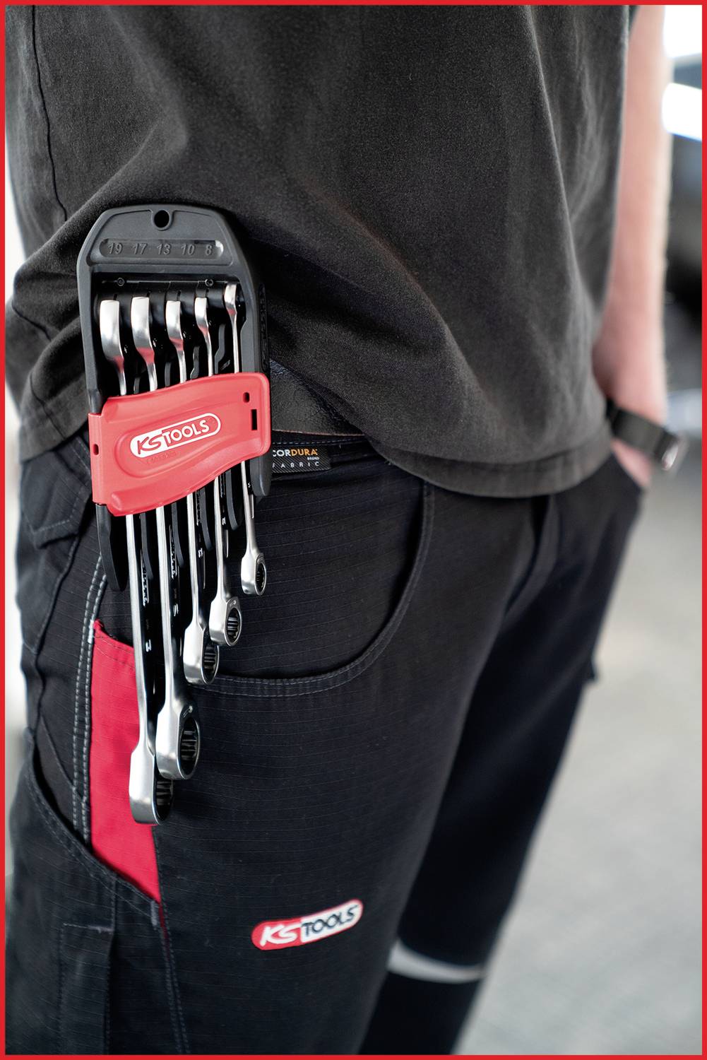 A person is wearing black workwear with a set of spanners attached to their trouser pocket.